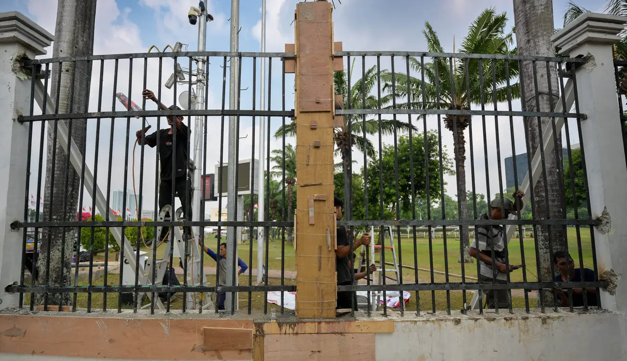 Para pekerja memasang kembali pagar besi kompleks parlemen yang dijebol oleh para demonstran pada hari sebelumnya, di Jakarta pada 23 Agustus 2024. (BAY ISMOYO/AFP)