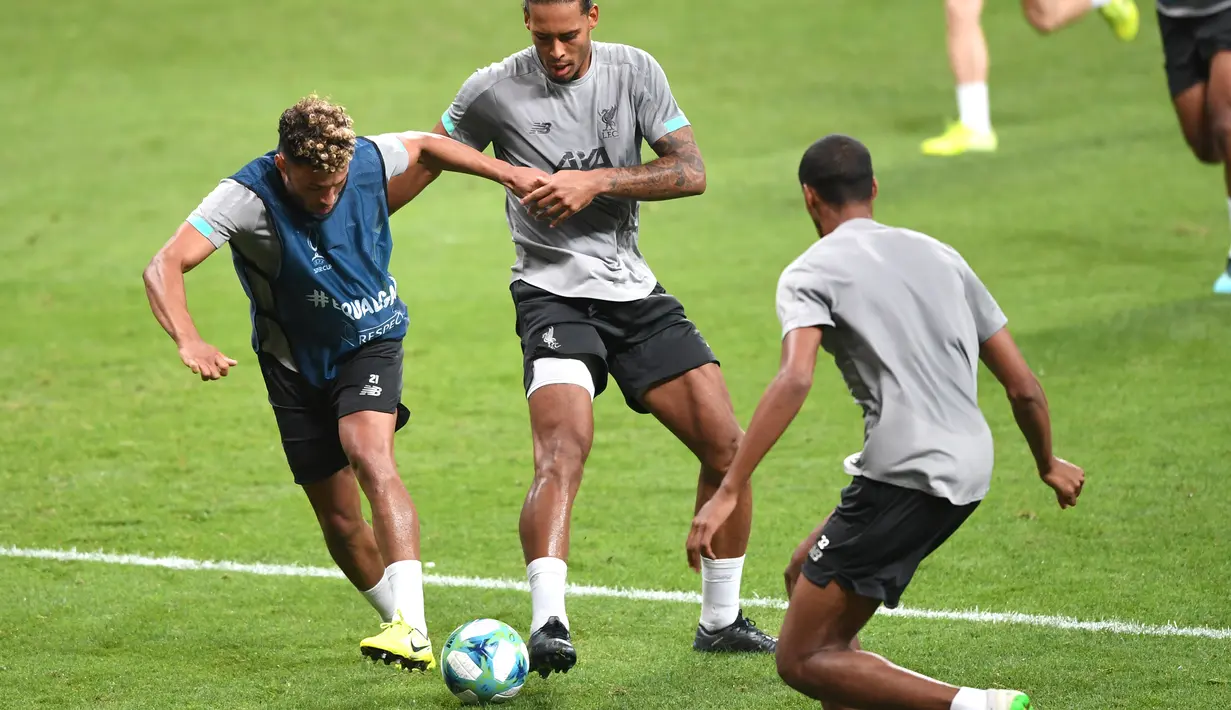 Gelandang  Liverpool, Alex Oxlade-Chamberlain (kiri) berusaha menggiring bola dari kawalan bek Virgil van Dijk (tengah) selama sesi latihan di stadion Besiktas Park di Istanbul, Turki (13/8/2019). Liverpool akan bertanding melawan Chelsea dalam pertandingan Piala Super Eropa 2019. (AFP Photo/Ozan Ko