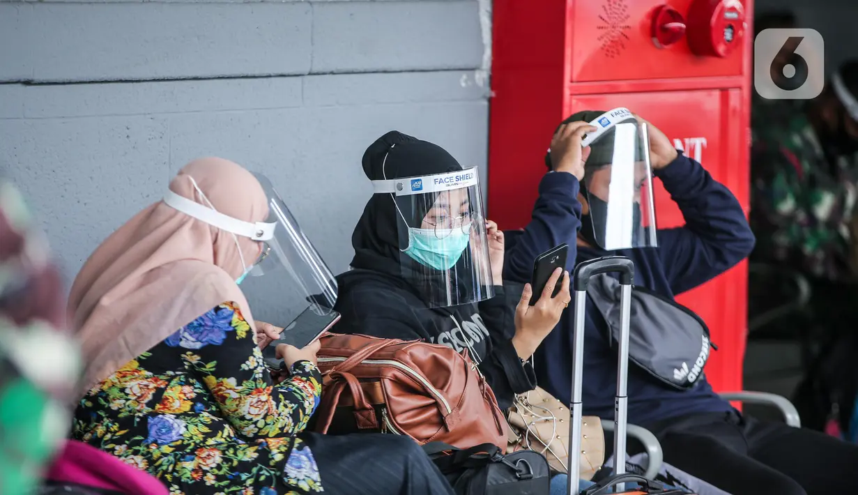 Penumpang menggunakan pelindung wajah menunggu kereta jarak jauh di Stasiun Pasar Senen, Jakarta, Jumat (10/7/2020). PT. KAI membagikan face shield kepada penumpang bertujuan memudahkan masyarakat tetap dapat menjaga physical distancing di tengah pandemi COVID-19. (Liputan6.com/Faizal Fanani)