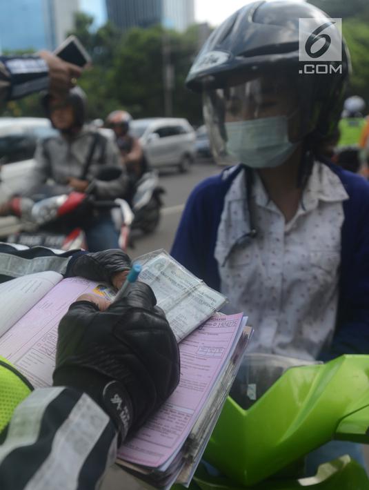 Polantas membuat surat tilang untuk pengendara motor ketika berlangsungnya Operasi Patuh Jaya 2018 di ruas Jalan DI Panjaitan, Jakarta Timur, Jumat (27/4). Razia ini berlangsung selama 14 hari, dari 26 April sampai 5 Mei 2018. (Merdeka.com/Imam Buhori)
