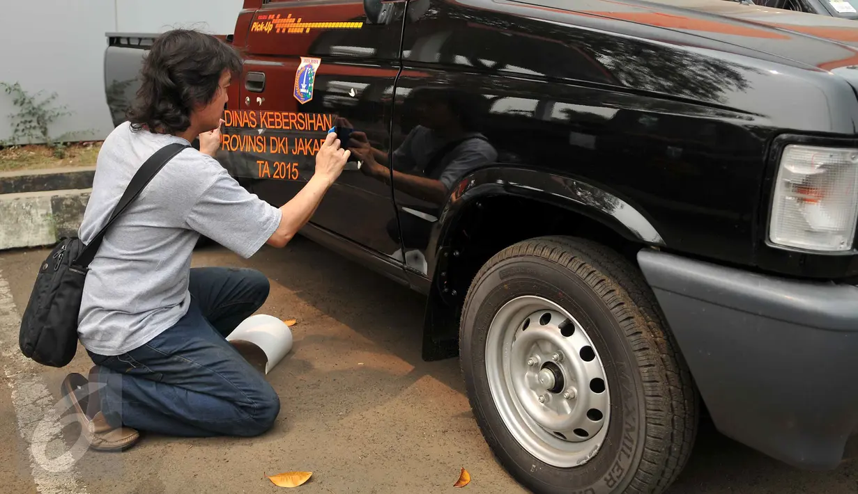 Seorang petugas memasang stiker pada kendaraan operasional di kantor Dinas Kebersihan DKI Jakarta, di Cililitan, Jumat (23/10). Sebanyak 77 mobil pick up diberikan sebagai kendaraan operasional pengawas kebersihan kota. (Liputan6.com/Gempur M Surya)