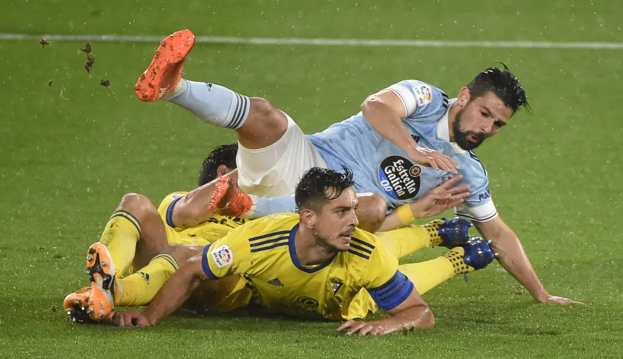 Penyerang Celta Vigo, Nolito, terjatuh saat berebut bola dengan pemain Cadiz pada laga lanjutan Liga Spanyol di Stadion Abanca Balaidos, Selasa (15/12/2020) dini hari WIB. Celta Vigo menang telak 4-0 atas Cadiz. (AFP/Miguel Riopa)