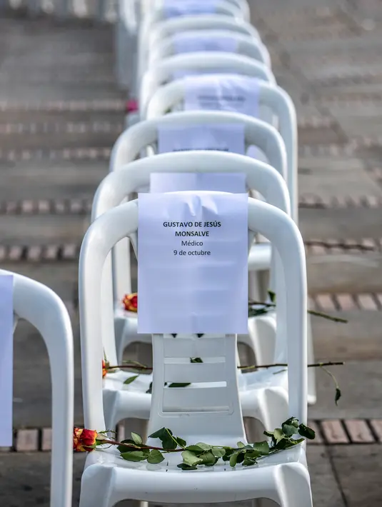 Bangku dengan nama petugas kesehatan yang meninggal karena COVID-19, pita hitam dan bunga, selama aksi protes terhadap sistem kesehatan di Bogota, Senin (26/10/2020). Kolombia pada Sabtu, 24 Oktober, melampaui satu juta kasus COVID-19 yang dikonfirmasi sejak dimulainya pandemi. (Juan BARRETO/AFP)