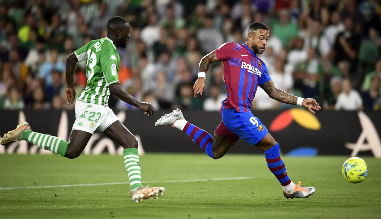 <p>Pemain Real Betis Youssouf Sabaly (kiri) berebut bola dengan pemain Barcelona Memphis Depay pada pertandingan sepak bola La Liga Spanyol di Stadion Benito Villamarin, Seville, Spanyol, 7 Mei 2022. Barcelona menang 2-1. (AP Photo/Jose Breton)</p>