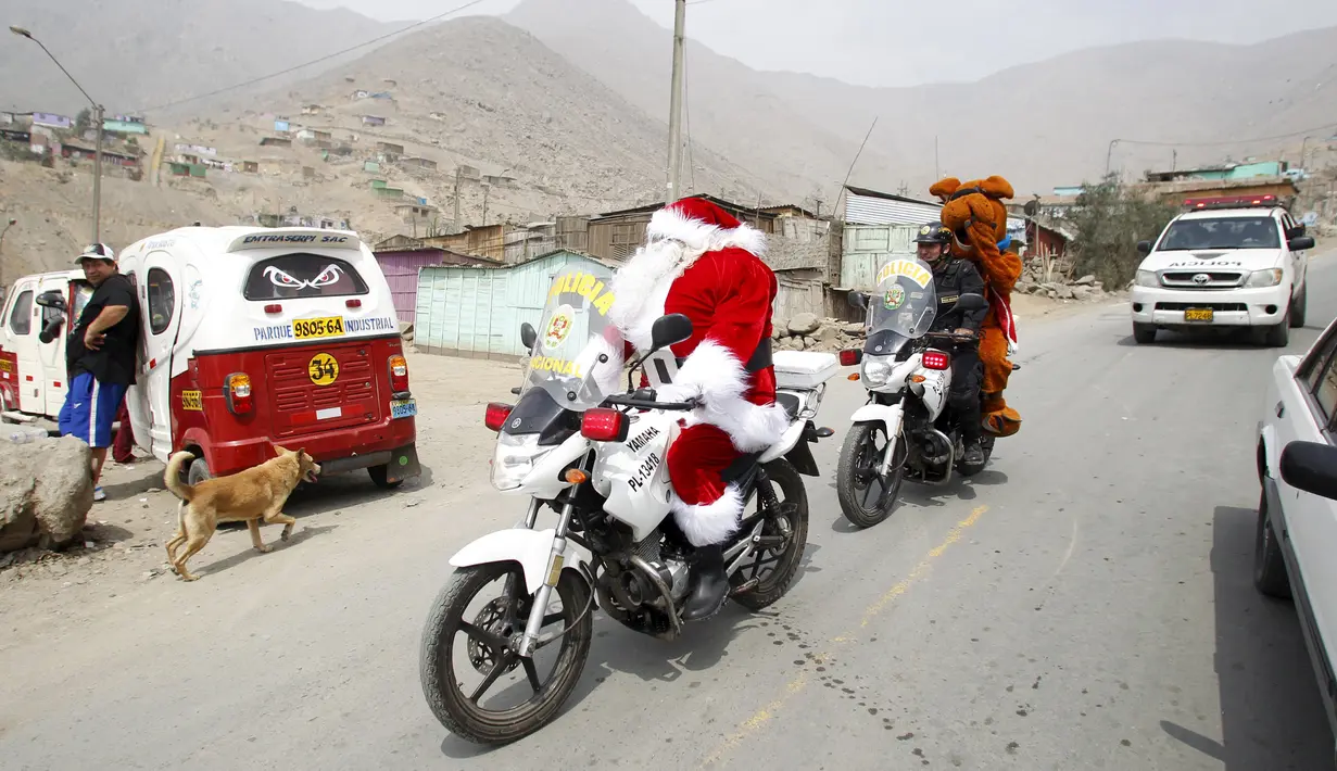 Seorang polisi Peru berpakaian seperti Santa Claus tiba dengan sepeda motornya selama perayaan Natal di Huaycan, Lima, Peru (15/12/2015). (REUTERS/Janine Costa)