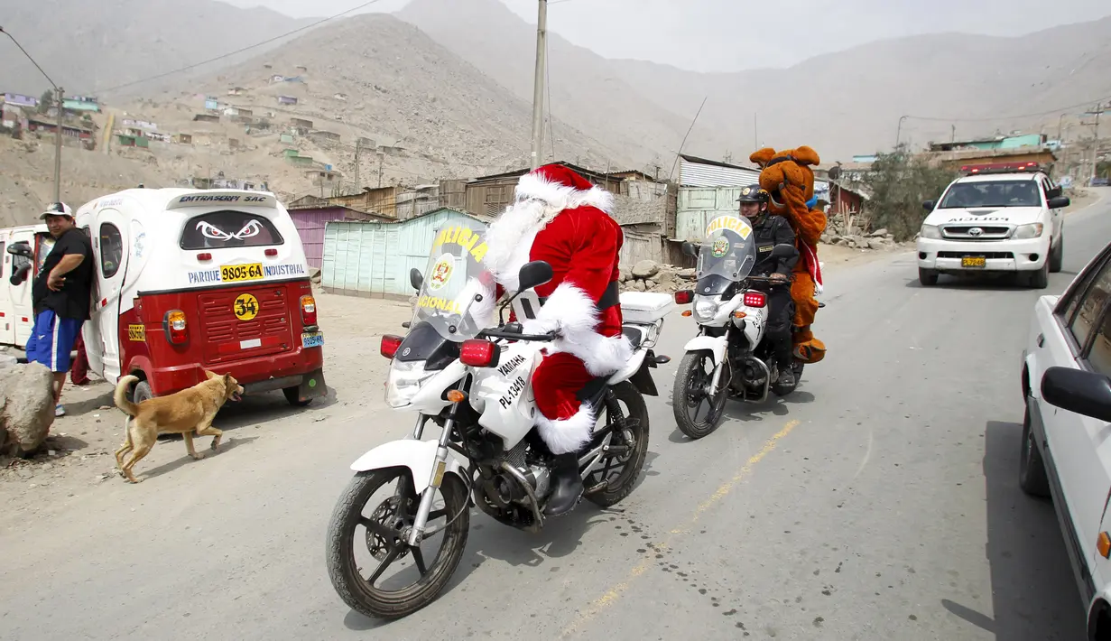 Seorang polisi Peru berpakaian seperti Santa Claus tiba dengan sepeda motornya selama perayaan Natal di Huaycan, Lima, Peru (15/12/2015). (REUTERS/Janine Costa)