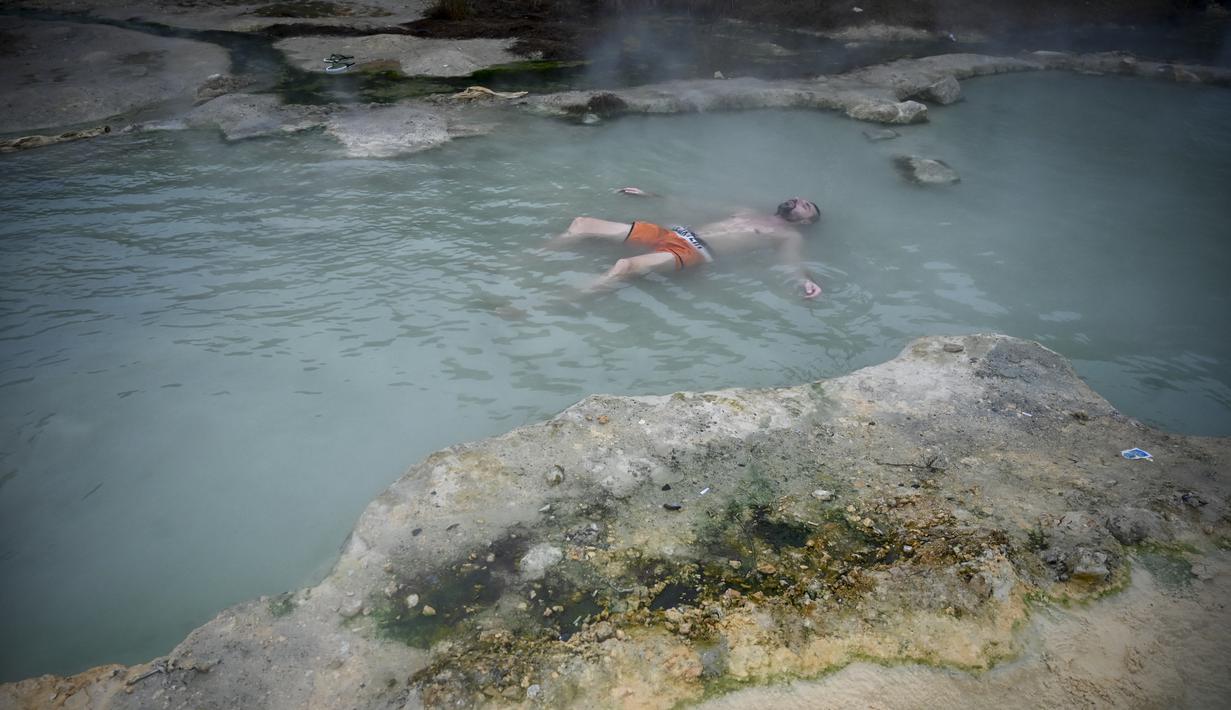 Seorang pria menikmati air panas di mata air mineral alami pada hari musim dingin di dekat desa Rupite, Bulgaria (2/2/2022). Penduduk setempat percaya bahwa air mineral menyembuhkan banyak penyakit dan gangguan. (AFP/Nikolay Doychinov)