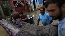 Warga membawa sofa saat membersihkan rumah mereka yang terendam banjir di Itapetinga, negara bagian Bahia, Brasil, Selasa (28/12/2021). Dua bendungan jebol pada Minggu (26/12) di timur laut Brasil, mengancam banjir yang lebih parah di wilayah yang diguyur hujan. (AP/Raphael Muller)
