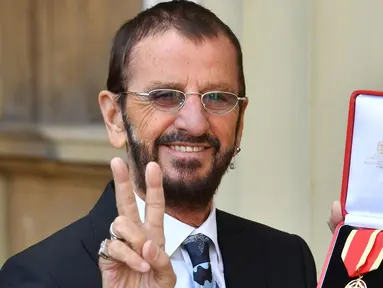 Ringo Starr berpose di Istana Buckingham, di London, Inggris (20/3). Mantan drummer The Beatles ini mendapat gelar kebangsawanan dari Pangeran William. Ia diberi gelar 'Sir' atas jasanya dalam dunia musik. (John Stillwell / Pool Photo via AP)