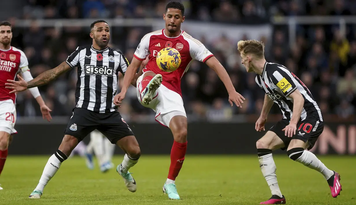 Penyerang Newcastle United Callum Wilson berebut bola dengan bek Arsenal William Saliba pada laga Premier League 2023/2024 pekan 11 yang digelar di St. James' Park, Minggu (5/11/2023) dini hari WIB. (Owen Humphreys/PA via AP)