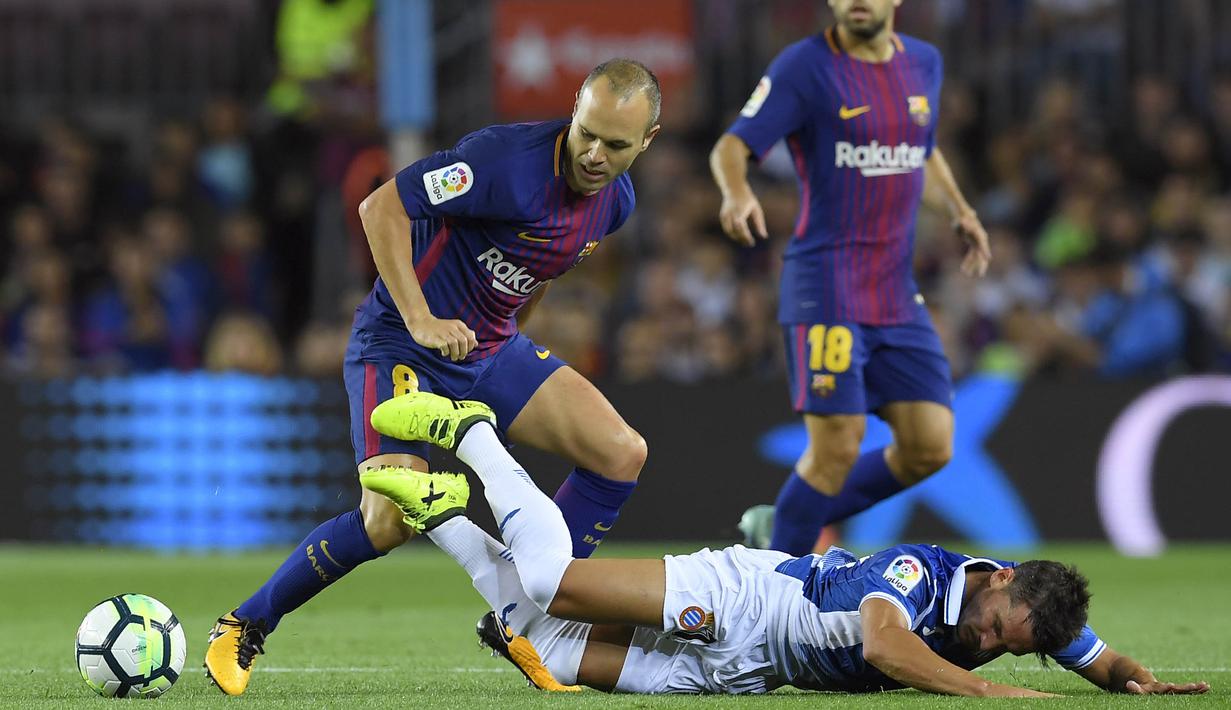 Gelandang Barcelona, Andres Iniesta, mengamankan bola dari tekel penyerang Espnayol, Daniel Piatti, pada laga La Liga Spanyol di Stadion Camp Nou, Katalonia, Sabtu (9/9/2017). Barcelona menang 5-0 atas Espanyol. (AFP/Lluis Gene)