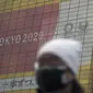 Seorang pria yang mengenakan masker berjalan di dekat spanduk Olimpiade dan Paralimpiade Tokyo 2020, di Tokyo, Jepang pada 27 Januari 2021. Olimpiade 2020 Tokyo yang ditunda terkait pandemi virus corona Covid-19 dijadwalkan ulang untuk diadakan pada musim panas ini.  (AP Photo/Eugene Hoshiko)