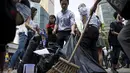 Beberapa pekerja kantor membersihkan lokasi terjadinya bentrok massa pro-demokrasi dan anti-demokrasi di daerah pusat bisnis Hong Kong, (13/10/2014). (REUTERS/Tyrone Siu)