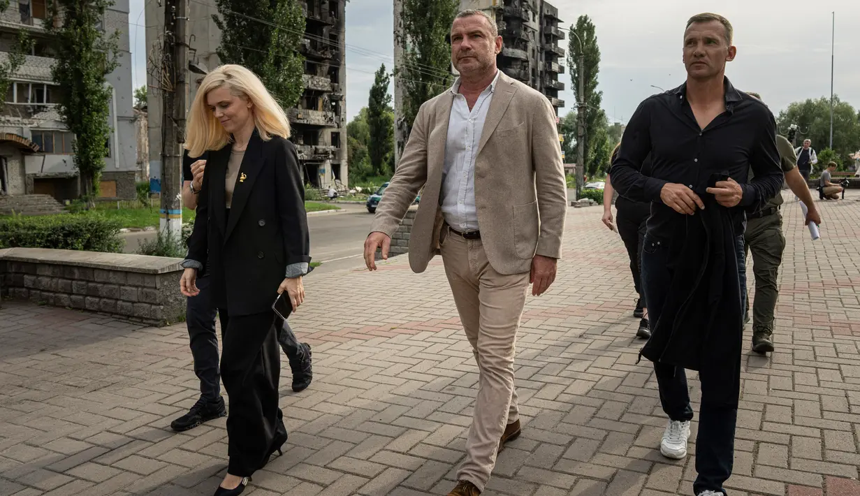 Mantan striker dan pelatih tim nasional sepak bola Ukraina Andriy Shevchenko (kanan) bersama aktor Amerika Serikat Liev Schreiber (tengah) berjalan di depan sebuah rumah yang telah dihancurkan oleh pemboman Rusia di Borodianka, dekat Kyiv, Ukraina, 15 Agustus 2022. Andriy Shevchenko merupakan duta besar platform penggalangan dana UNITED24 yang diluncurkan oleh Presiden Ukraina Volodymyr Zelenskyy sebagai tempat utama untuk mengumpulkan sumbangan amal untuk mendukung Ukraina. (AP Photo/Evgeniy Maloletka)