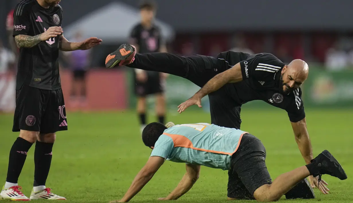 Pengawal Lionel Messi, Yassine Cheuko terjatuh saat berusaha menangkap seorang penyusup lapangan dalam laga persahabatan antara Inter Miami melawan Sporting San Miguelito di Stadion Romeo Fernandez, Panama, Amerika, Senin (03/02/2025) waktu setempat. (AP Photo/Matias Delacroix)