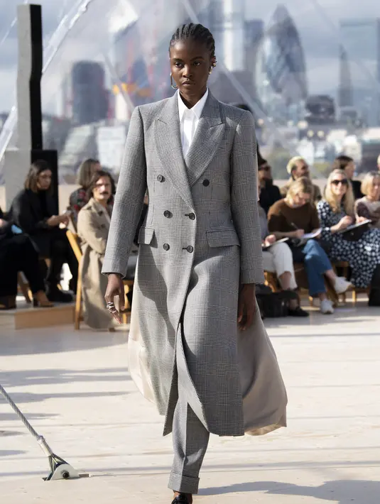 Setelan coat wol kotak-kotak bermodel double-breasted Prince of Wales dan high-waisted peg trousers dipadu secara kontras dengan kemeja katun poplin putih berbahan poly faille. Foto: Document/Alexander McQueen.