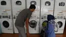 Petugas membantu seorang ibu rumah tangga menaruh cucian di sebuah laundry koin di Jakarta, Sabtu (8/6/2019). Pada libur Lebaran, jasa laundry ramai didatangi konsumen, terutama oleh mereka yang ditinggal mudik asisten rumah tangganya. (merdeka.com/Imam Buhori)