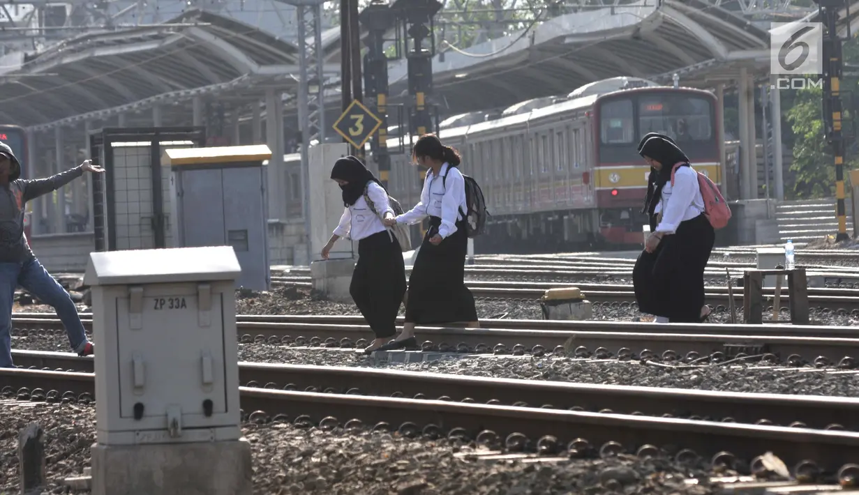 Sejumlah pelajar menyeberangi perlintasan rel kereta api di kawasan Pisangan Baru, Jakarta, Selasa (10/9/2019). Mereka nekat menantang maut menyeberangi rel di dekat stasiun Jatinegara tersebut lantaran tidak adanya akses jembatan penyeberangan orang (JPO). (merdeka.com/Iqbal Nugroho)