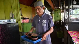 Seorang pria membawa kopi Kawa Daun di sebuah kafe tradisional di Tabek, Sumatera Barat (29/11).  Keunikan kopi di daerah ini adalah minuman yang mengekstrak rasa dari daun tanaman daripada kacangnya. (AFP Photo/Adek Berry)