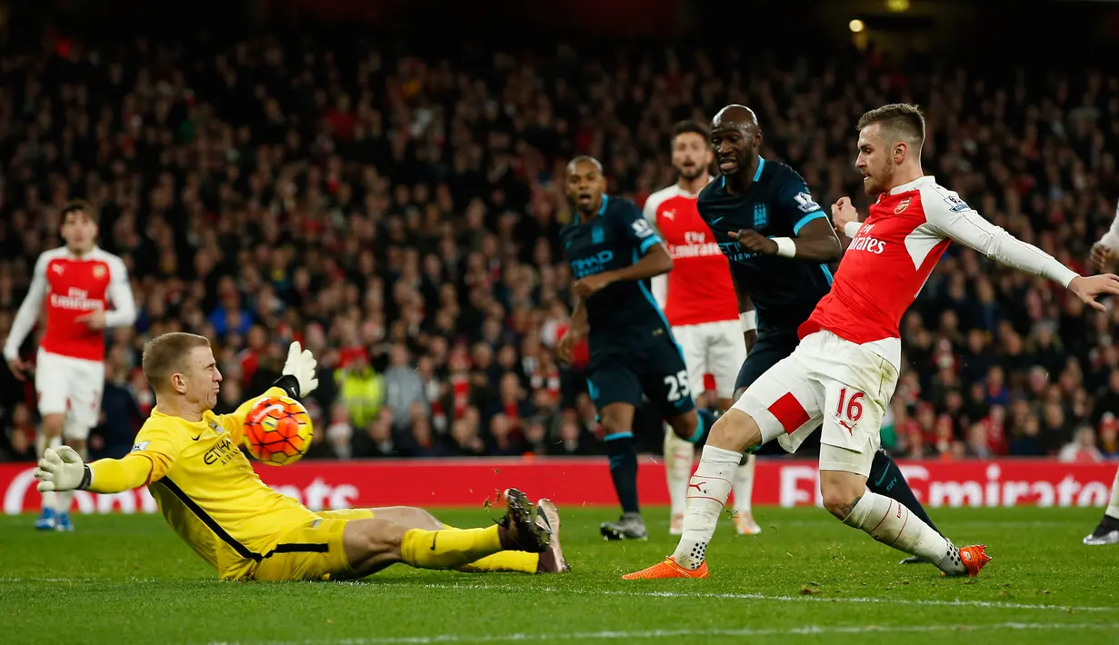 Kiper Mancheseter City, Joe Hart berusaha menghalau tendangan gelandang Arsenal,  Aaron Ramsey pada lanjutan liga Inggris di Stadion Emirates (21/12). Arsenal menang atas City dengan skor 2-1. (Reuters/John Sibley)