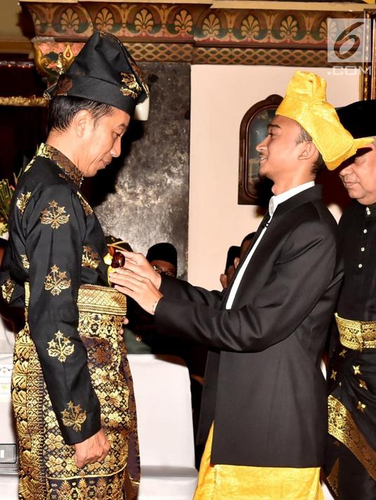 Presiden Joko Widodo menerima penyematan pin dan keris dari Sultan Deli, Tuanku Mahmud Lamantjiji Perkasa Alam saat menerima gelar Tuanku Sri Indera Utama Junjungan Negeri dari Kesultanan Deli di Istana Maimoon, Minggu (6/10). (Liputan6.com/HO/Biropers)