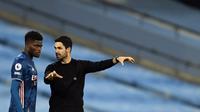 Pemain Arsenal, Thomas Partey, mendengarkan instruksi dari sang manajer, Mikel Arteta, ketika akan menjalani debut bersama The Gunners dalam laga kontra Manchester City, Minggu (18/10/2020). (AFP/MICHAEL REGAN)