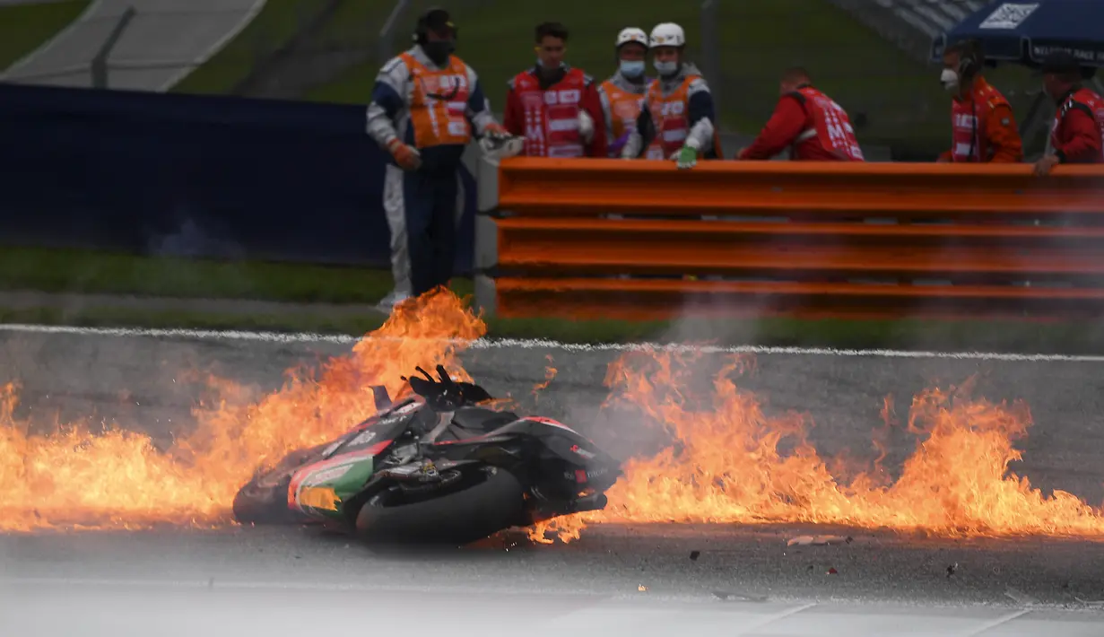 Sepeda motor terbakar menyusul kecelakaan yang melibatkan pembalap Aprilia Gresini, Lorenzo Savadori dan pembalap KTM, Dani Pedrosa saat MotoGP Styria 2021 di Red Bull Ring, Minggu (8/8/2021). Savadori harus ditandu untuk pemeriksaan medis sementara Pedrosa lolos cedera serius. (JOE KLAMAR/AFP)