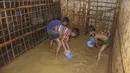 Anak-anak pengungsi Rohingya mengeluarkan air banjir dari rumah mereka di kamp pengungsi Rohingya di Kutupalong, Bangladesh (28/7/2021). Ribuan pengungsi kehilangan tempat tinggal akibat banjir tersebut. (AP Photo/Syafiqur Rahman)