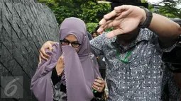 Istri Hakim MK Patrialis Akbar, Sufriyeni (kiri) menutup wajah saat menuju ruang tahanan KPK, Jakarta, Senin (30/1). Patrialis Akbar menjadi tersangka dugaan penerima suap uji materi UU peternakan dan Kesehatan Hewan. (Liputan6.com/Helmi Fithriansyah)