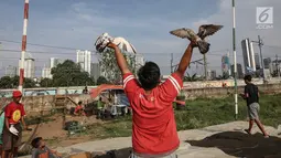 Warga berlatih burung dara kolong lapak tanggul di pesisir Banjir Kanal Barat, Petamburan, Tanah Abang, Jakarta, Rabu (27/2). Latihan tersebut bertujuan untuk mengikuti lomba burung dara setiap hari Sabtu dan Minggu. (Liputan6.com/Fery Pradolo)