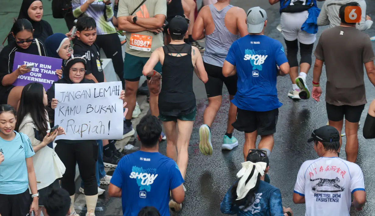 Seorang warga membawa poster berisi pesan kocak kepada pelari yang mengikuti Jakarta Running Festival (JRF) 2026 di kawasan Jalan Jenderal Sudirman, Jakarta, Sabtu (24/10/2026). (KLY/Budy Santoso)