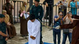 Terpidana pelanggaran syariat Islam menjalani hukum cambuk di Banda Aceh, Senin (21/10/2019). Mahkamah Syariah menvonis 6 kali sabetan cambuk setelah dipotong masa tahanan dua kali cambuk terhadap empat orang pria berprofesi sopir setelah tertangkap sedang bermain judi. (CHAIDEER MAHYUDDIN / AFP)