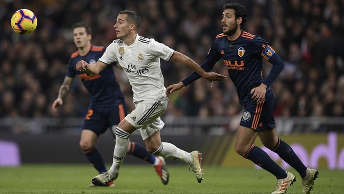 Striker Real Madrid, Lucas Vazquez, beradu cepat dengan gelandang valencia, Daniel Parejo, pada laga La Liga di Stadion Santiago Bernabeu, Madrid, Sabtu (1/12). Madrid menang 2-0 atas Valencia. (AFP/Oscar Del Pozo)