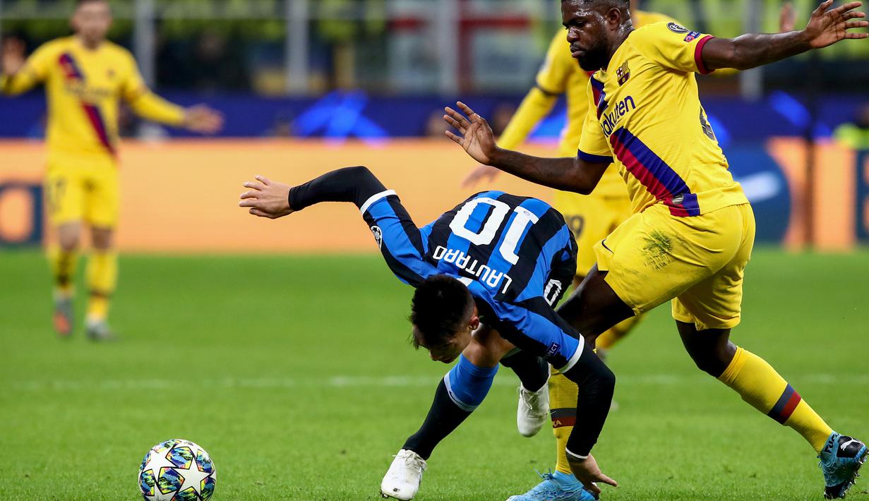 Striker Inter Milan, Lautaro Martinez, dijatuhkan bek Barcelona, Samuel Umtiti,  pada laga Liga Champions di Stadion San Siro, Milan, Selasa (10/12). Inter kalah 1-2 dari Barcelona. (AFP/Isabella Bonotto)