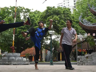 Pemuda Vietnam memainkan permainan "da cau" atau bulutangkis menggunakan bagian tubuh di dalam kompleks kuil Budha di Hanoi pada 25 Oktober 2019. Da Cau mirip dengan bulutangkis, tetapi tidak menggunakan raket untuk memukul kok, melainkan menggunakan setiap bagian tubuh.  (Nhac NGUYEN / AFP)