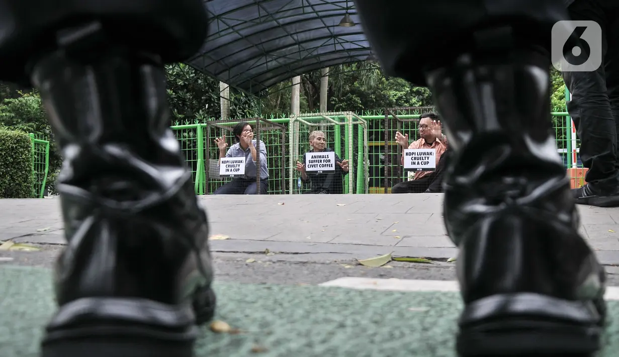 Aktivis People for the Ethical Treatment of Animals (PETA) mengurung diri di dalam kandang saat aksi teatrikal mengecam eksploitasi luwak untuk kepentingan produksi kopi di depan Kantor Kementerian Lingkungan Hidup dan Kehutanan (KLHK), Jakarta, Rabu (25/1/2023). Aktivis PETA mengurung diri di dalam kandang sebagai bentuk protes dan mendesak pihak berwenang melarang peternakan luwak untuk kepentingan produksi kopi. (merdeka.com/Iqbal S Nugroho)