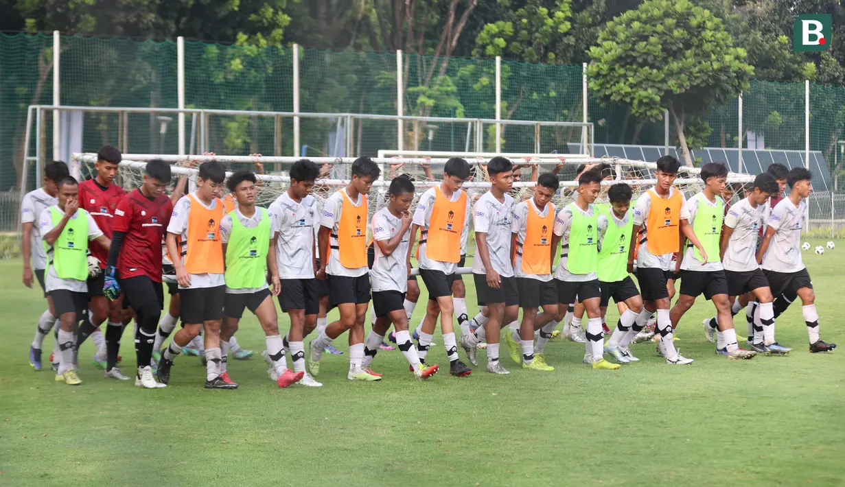 Sejumlah pemain bahu membahu mengangkat gawang saat sesi latihan di Lapangan ABC, Kompleks Gelora Bung Karno, Kamis (27/7/2023). (Bola.com/Abdul Aziz)