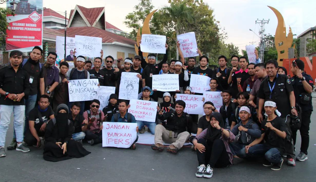 Massa yang tergabung dalam Aliansi Jurnalis Gorontalo membawa sejumlah poster saat menggelar aksi menolak RUU KUHP di Gorontalo, Senin (23/9/2019). Aliansi Jurnalis Gorontalo dengan tegas mengecam dan menolak RUU KUHP. (Liputan6.com/Arfandi Ibrahim)