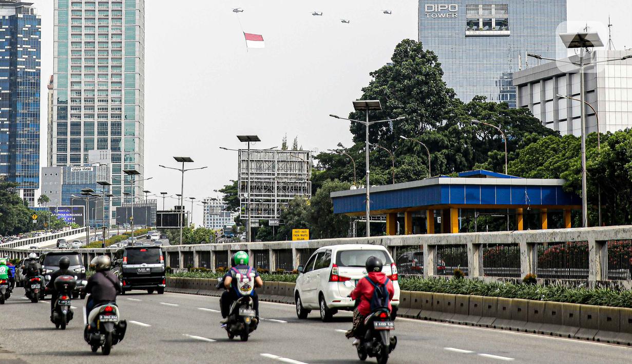 Helikopter TNI AU mengibarkan bendera Merah Putih raksasa di kawasan Gedung DPR RI, Jakarta, Selasa (5/10/2021). Bendera yang dikibarkan berukuran 30 x 20 meter. (Liputan6.com/Faizal Fanani)