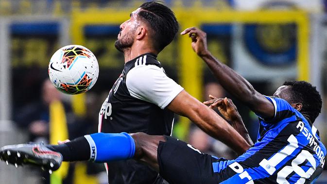 Pemain bertahan Inter Milan, Kwadwo Asamoah berebut bola dengan pemain Juventus, Emre Can dalam lanjutan kompetisi Serie A 2019-2020 di Stadion Giuseppe Meazza, Minggu (6/10/2019). Juventus memenangi duel bertajuk Derby d'Italia dengan keunggulan 2-1 atas Inter. (Alberto PIZZOLI / AFP)