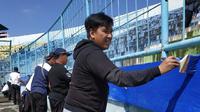 Media Officer Arema, Sudarmaji, ikut acara mengecat tribune Stadion Kanjuruhan. (Bola.com/Iwan Setiawan)