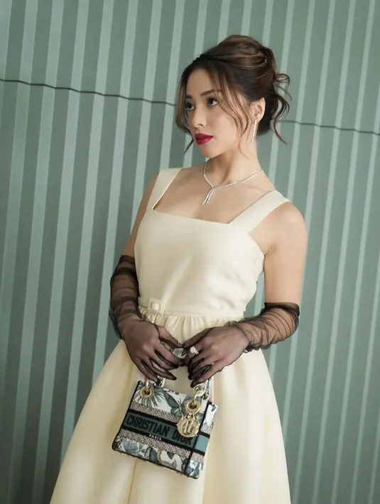 Tampil anggun bak Audrey Hepburn, Nikita Willy kenakan dress bertali lebar putih. Dipadukan dengan gloves hitam transparan hitam dan tas Lady Dior. [@nikitawillyofficial94]