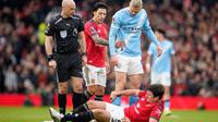 Harry Maguire dari Manchester United, di bagian bawah, tergeletak di lapangan kesakitan sementara wasit Anthony Taylor, Lisandro Martinez dari Manchester United, dan Erling Haaland dari Manchester City bereaksi selama pertandingan Liga Inggris antara Manchester United dan Manchester City di Manchester, Inggris, Sabtu, 17 Januari 2026. (AP Photo/Dave Thompson)