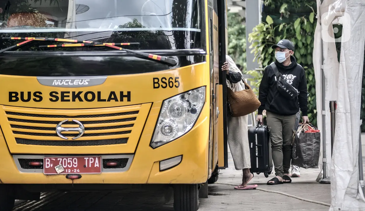 Sejumlah pasien COVID-19 memasuki bus sekolah untuk dipindahkan ke Wisma Atlet di Puskesmas Kecamatan Duren Sawit, Jakarta, Senin (28/12/2020). Tim Gugus Tugas Penanganan COVID-19 Puskesmas Kecamatan Duren Sawit hari ini memindahkan 14 pasien COVID-19. (merdeka.com/Iqbal S. Nugroho)