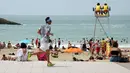Seorang pria joging saat orang-orang menikmati pantai dekat Samudra Atlantik di Biarritz, Prancis, 14 Juni 2022. Cuaca panas diperkirakan akan berlangsung selama beberapa hari di seluruh Prancis. (AP Photo/Bob Edme)