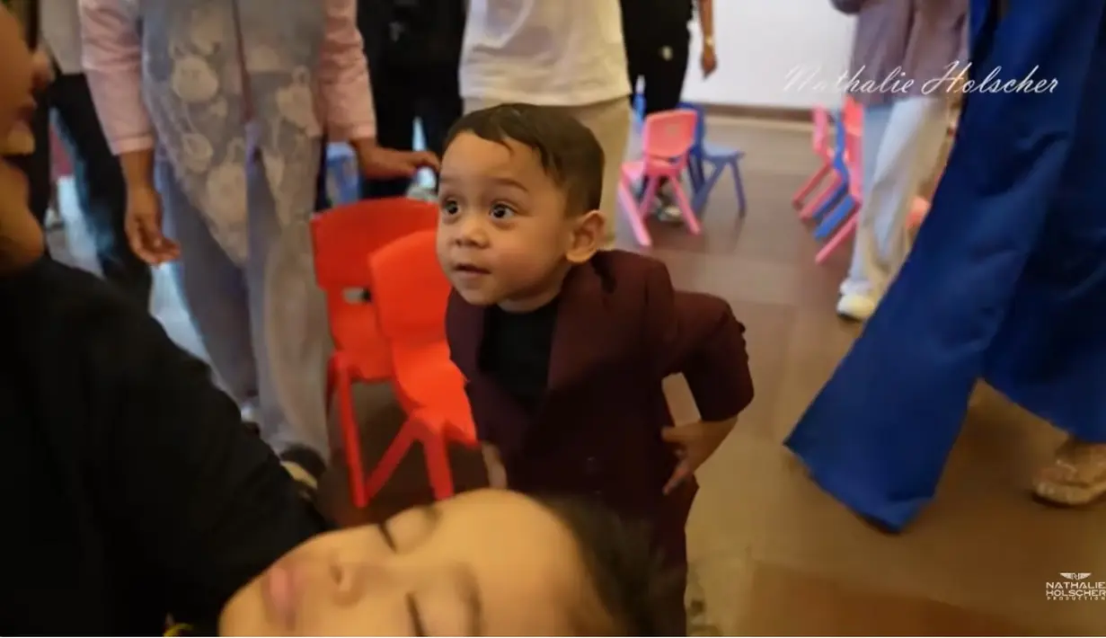 Tidak hanya para selebriti yang berhasil menarik perhatian, penampilan anak-anak selebriti juga tak kalah menarik perhatian. Penampilan Abang L anak Lesti dan Rizky Billar tampak menggemaskan denga setelan jaz. Momen Abang L saat akan membangunkan Adzam yang tidur. [Youtube/NATHALIE HOLSCHER]