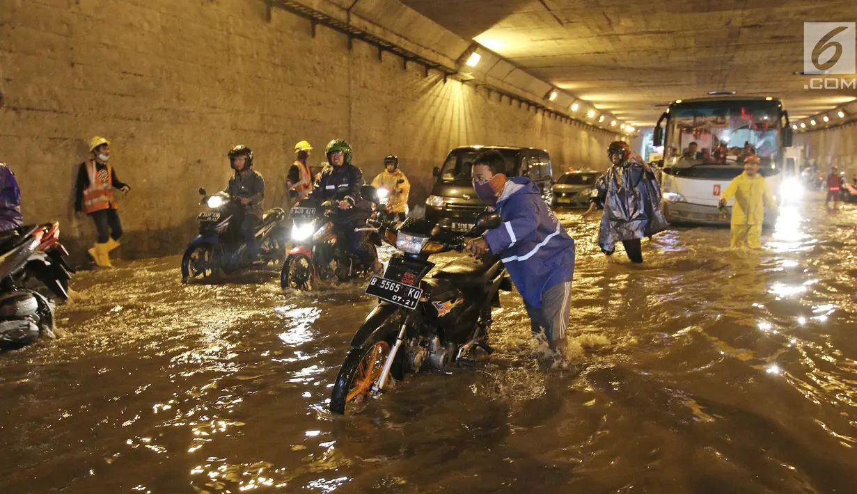 Pengendara mendorong motornya menerobos banjir di underpass Cawang, Jalan MT Haryono, Jakarta, Selasa (12/12). Hujan deras dan buruknya drainase di kawasan tersebut menjadi penyebab utama adanya genangan air hingga 50 cm. (Liputan6.com/Herman Zakharia)