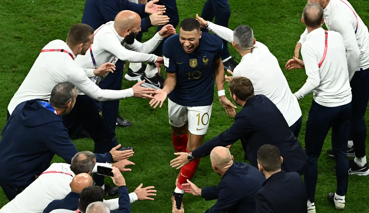 Penyerang #10 Prancis Kylian Mbappe merayakan bersama para pelatih setelah kemenangan tim timnya atas Inggris pada laga perempat final Piala Dunia 2022 di Al Bayt Stadium, Minggu (11/12/2022) dini hari WIB. Pada pertandingan tersebut, Prancis menang dengan skor 2-1 atas Inggris dan lolos ke babak semifinal. (Jewel SAMAD / AFP)
