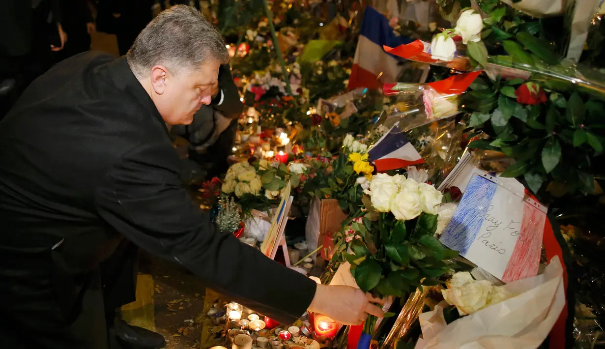 Presiden Ukraina Petro Poroshenko meletakkan bunga di salah satu lokasi serangan berdarah Paris di gedung konser Bataclan, Prancis, Minggu (30/11). (REUTERS/Gonzalo Fuentes)