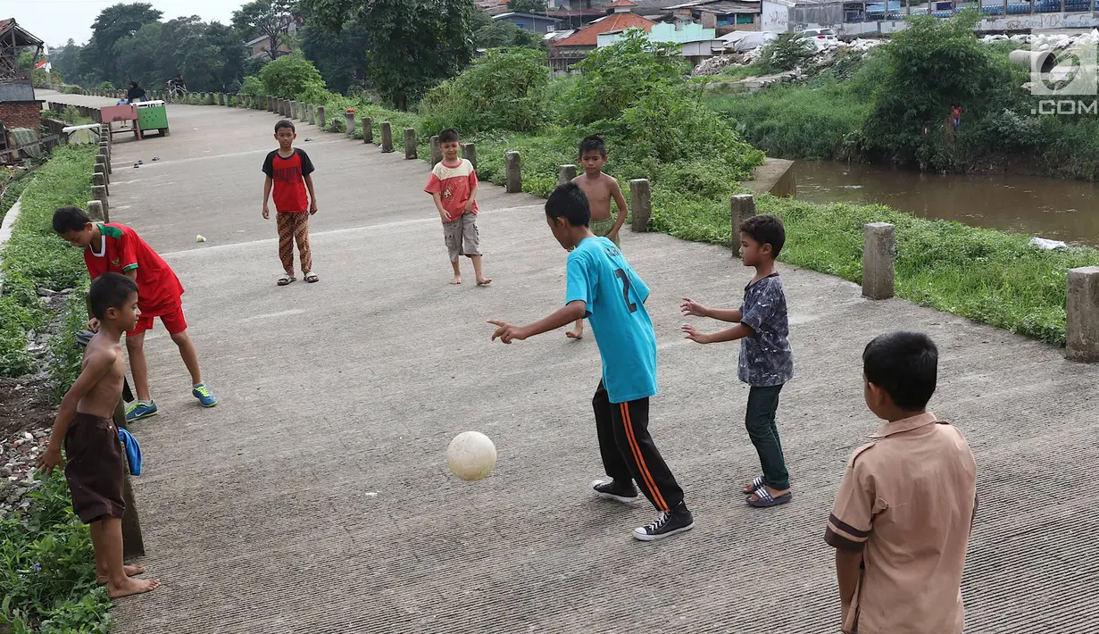 Anak-anak bermain sepak bola di jalur inspeksi Sungai Ciliwung di kawasan Rawajati, Jakarta, Rabu (23/1). Keterbatasan lahan tidak menyurutkan semangat mereka untuk bermain sepak bola meski di tempat seadanya. (Liputan6.com/Immanuel Antonius)